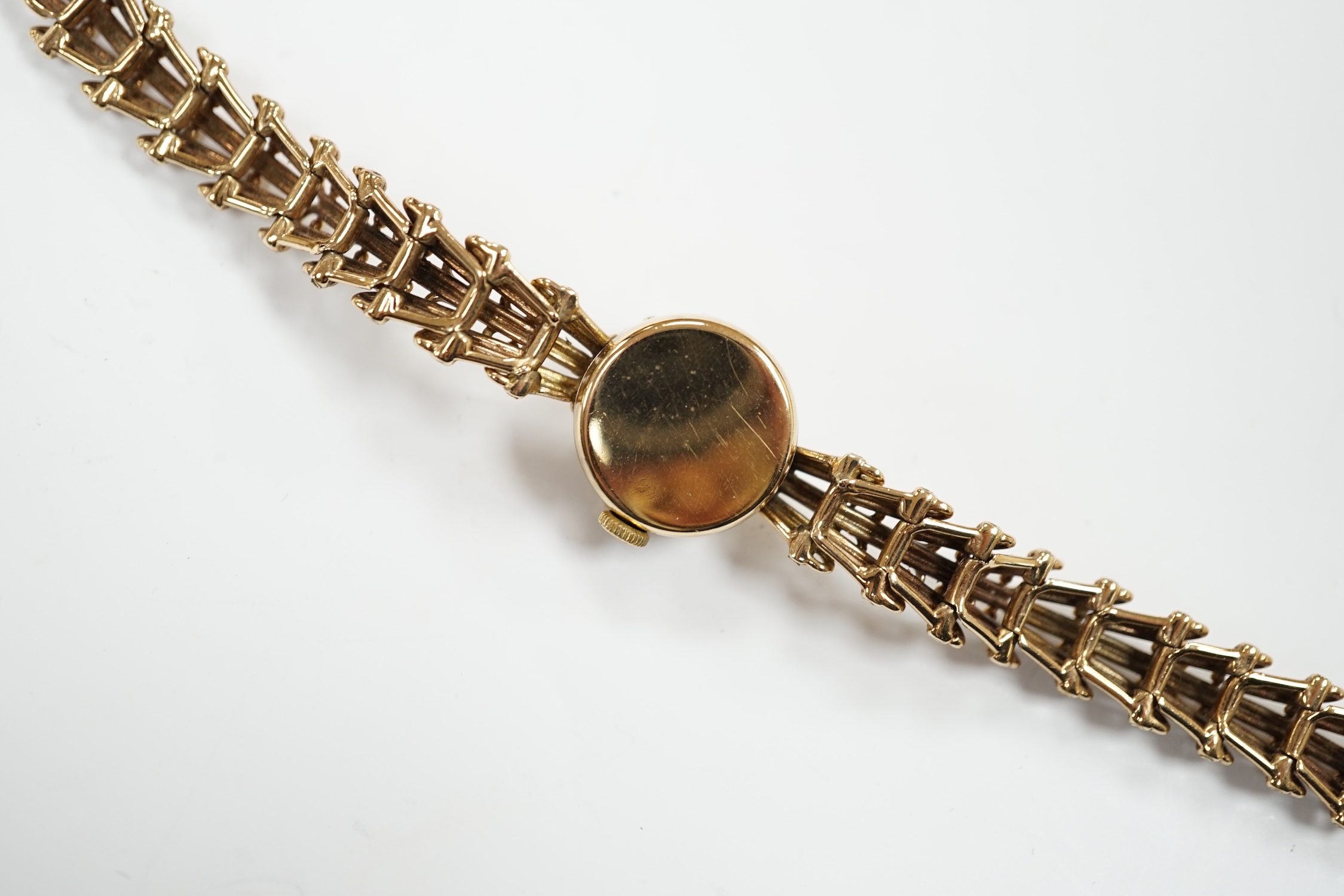 A lady's yellow metal manual wind bracelet watch, the dial with ruby and diamond cluster set hinged cover, overall length 16.3cm